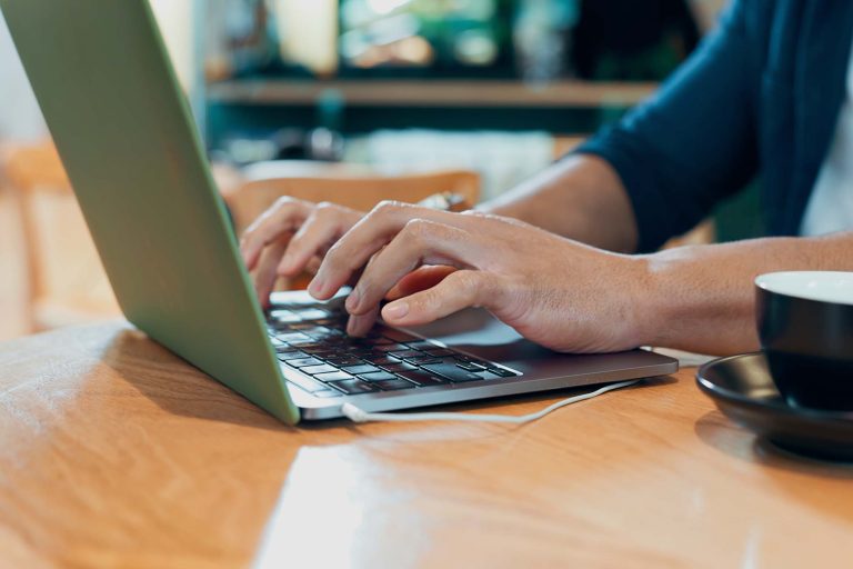hands-typing-computer-and-coffee-shop-for-remote-W9HVW84