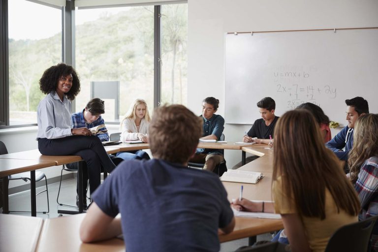 female-high-school-tutor-sitting-at-table-with-pup-CVSJ8WF